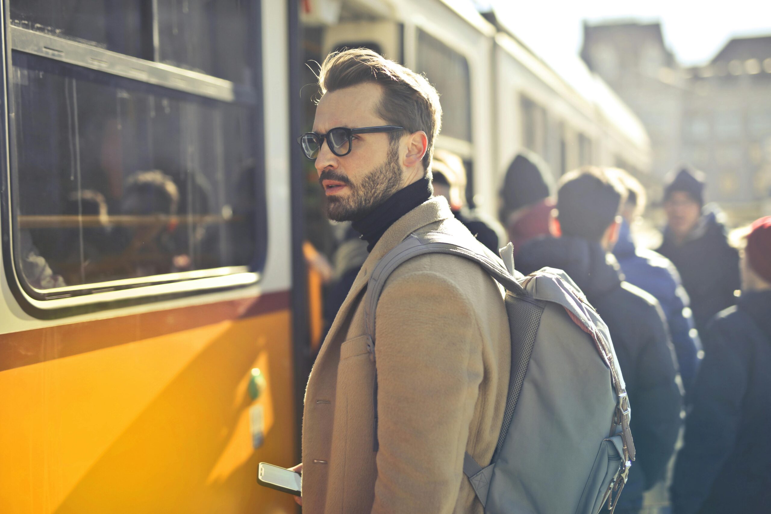 A stylish man with a backpack boards a tram in bustling Budapest, Hungary, during the day. pexels-photo-837358-837358